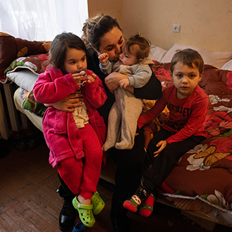 A mother and her children sitting on a bed. Links to Gifts That Protect Your Assets